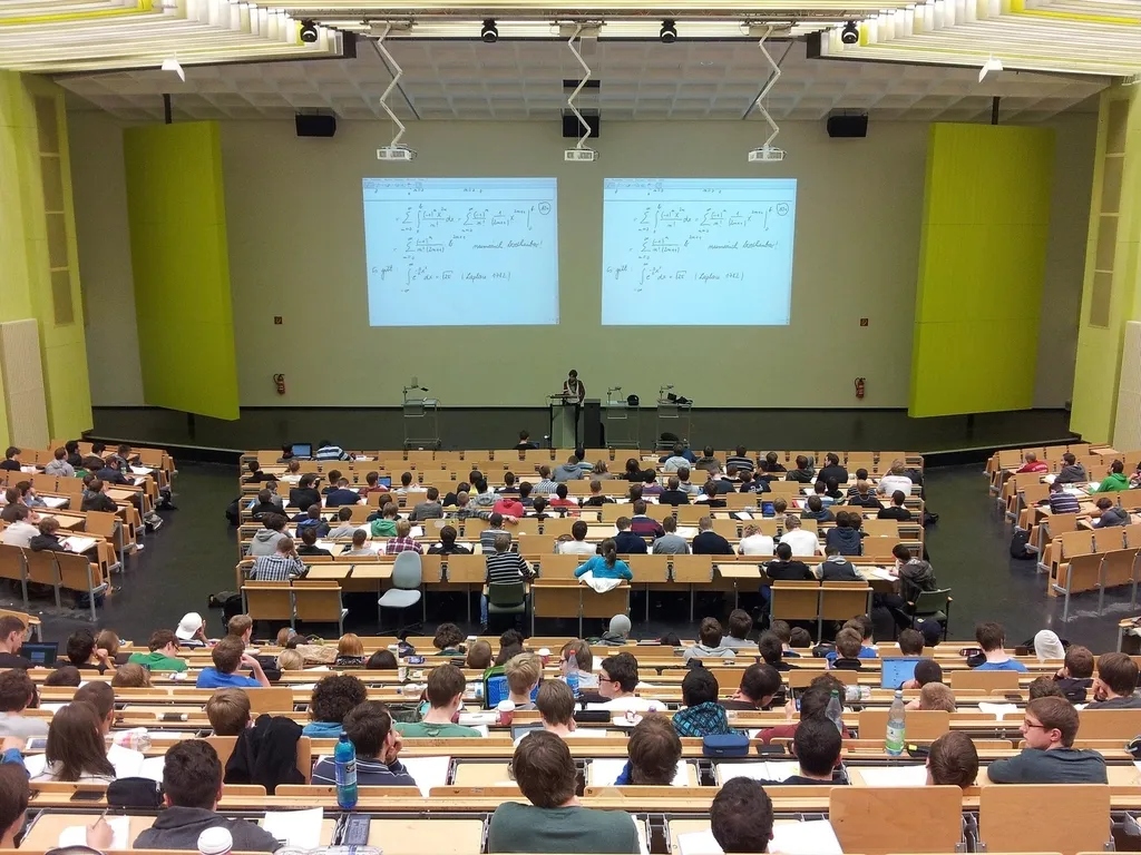 Students seated in a large lecture hall facing a projected slide