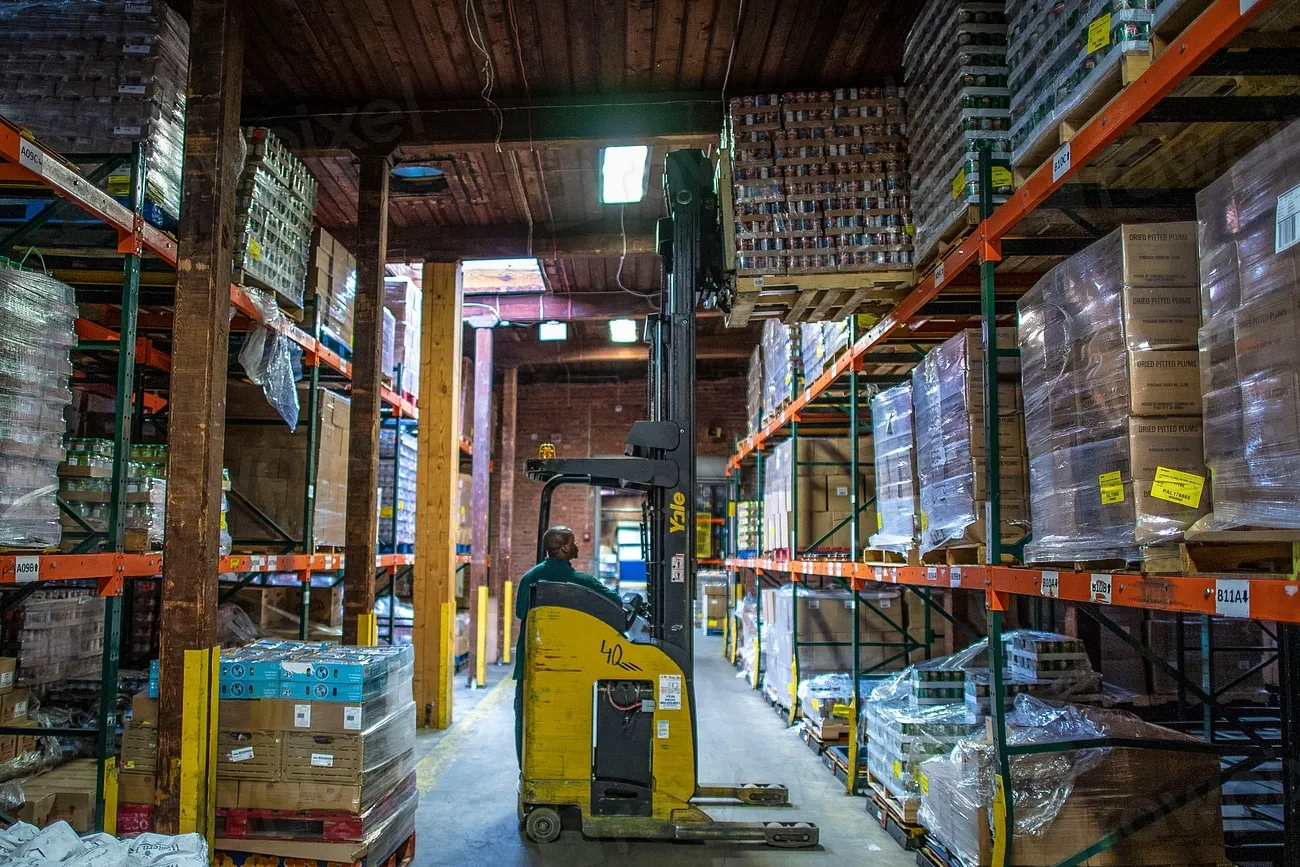 Warehouse aisle between tall pallet racks with a forklift